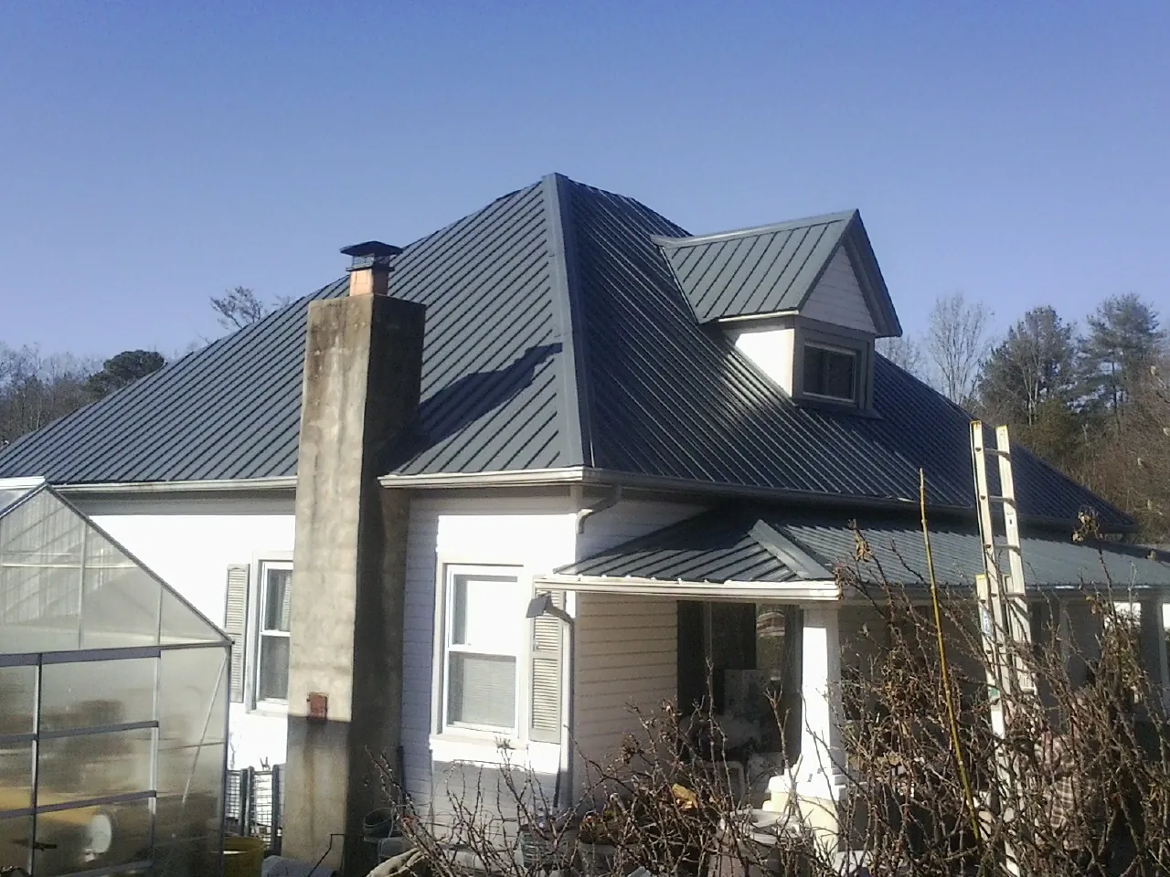 Dark blue standing seam metal roof on a white farmhouse with dormer — Slate & Tile Roof Repair by Roofing Brothers in Willow Street