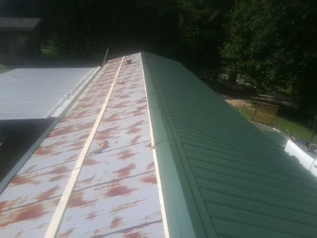 Old rusted panels beside newly installed green metal roofing — Wind Damage Roof Repair by Roofing Brothers in Willow Street