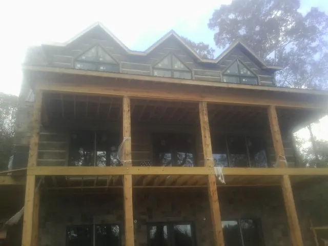 Dormers and porch framing on a large log home under construction — Roof Coating work by our crew in Willow Street