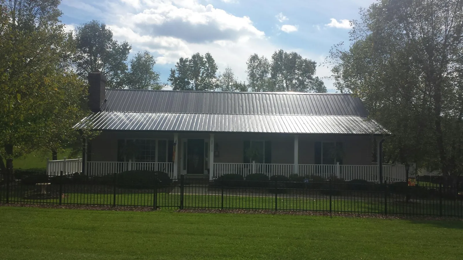 Gray metal roof on a brick ranch with a full width front porch — Gutter Guard Installation work by our crew in Willow Street