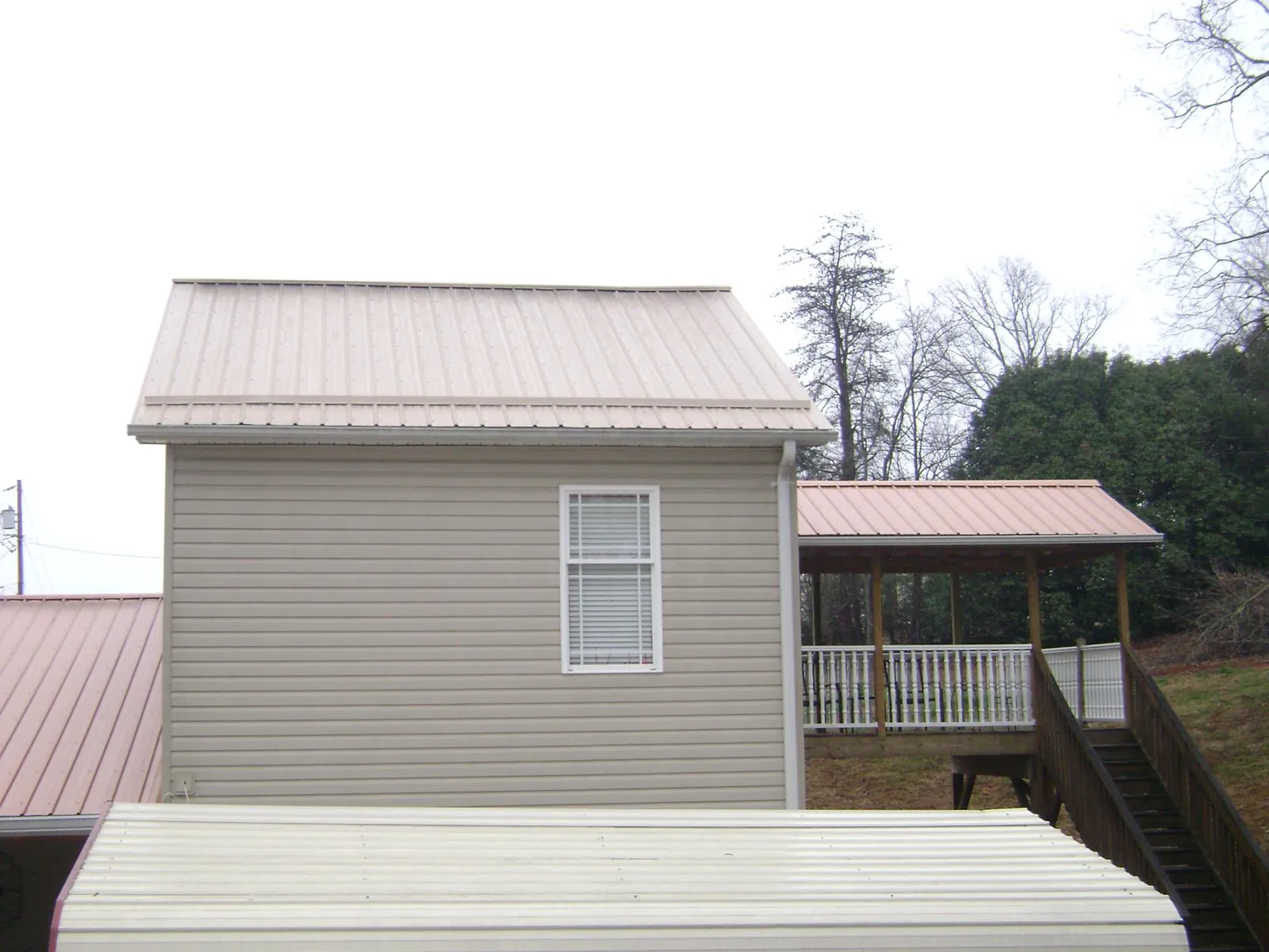 Tan metal roofs on a two story addition and attached porch, from a Roof Replacement job in Willow Street
