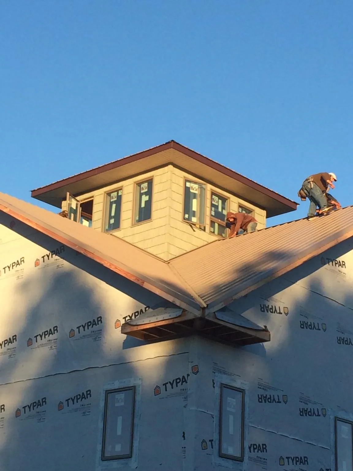 Roofers working around a rooftop cupola on a new metal roof at sunset — Roof Waterproofing in Willow Street by Roofing Brothers